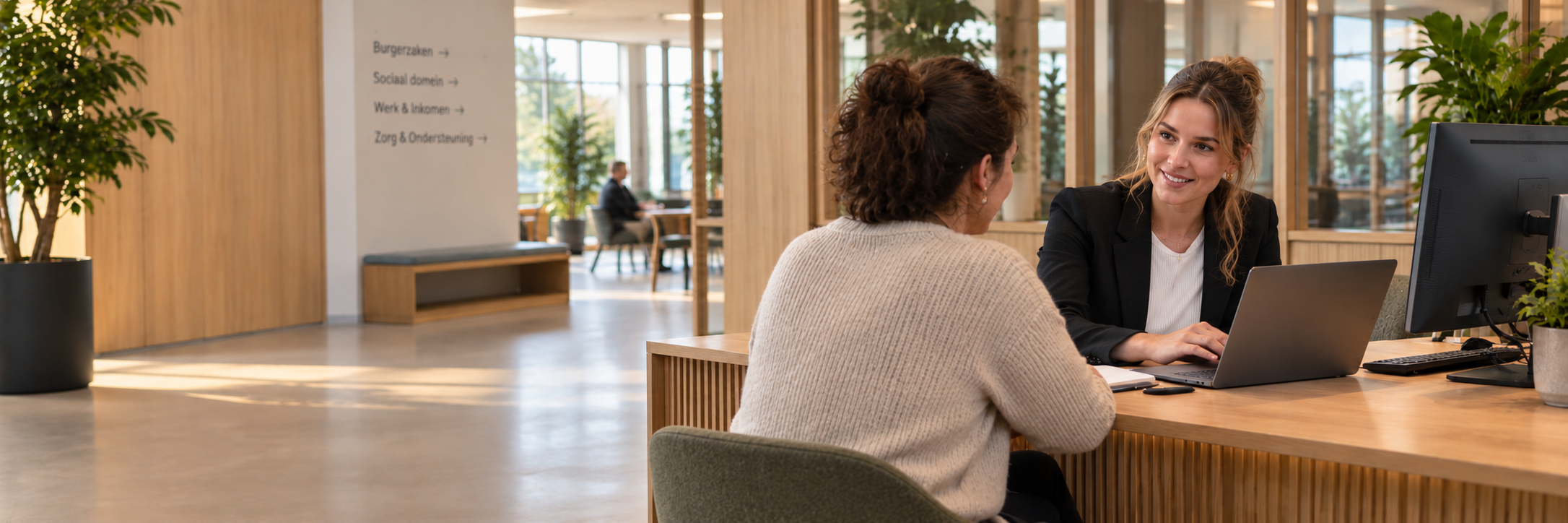 Gemeentemedewerker in gesprek met een inwoner aan de balie van het gemeentehuis