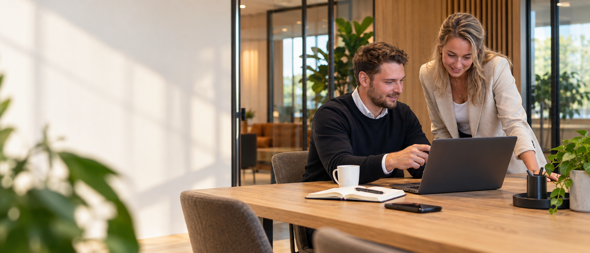 Twee collega's bekijken samen een laptop in een modern kantoor